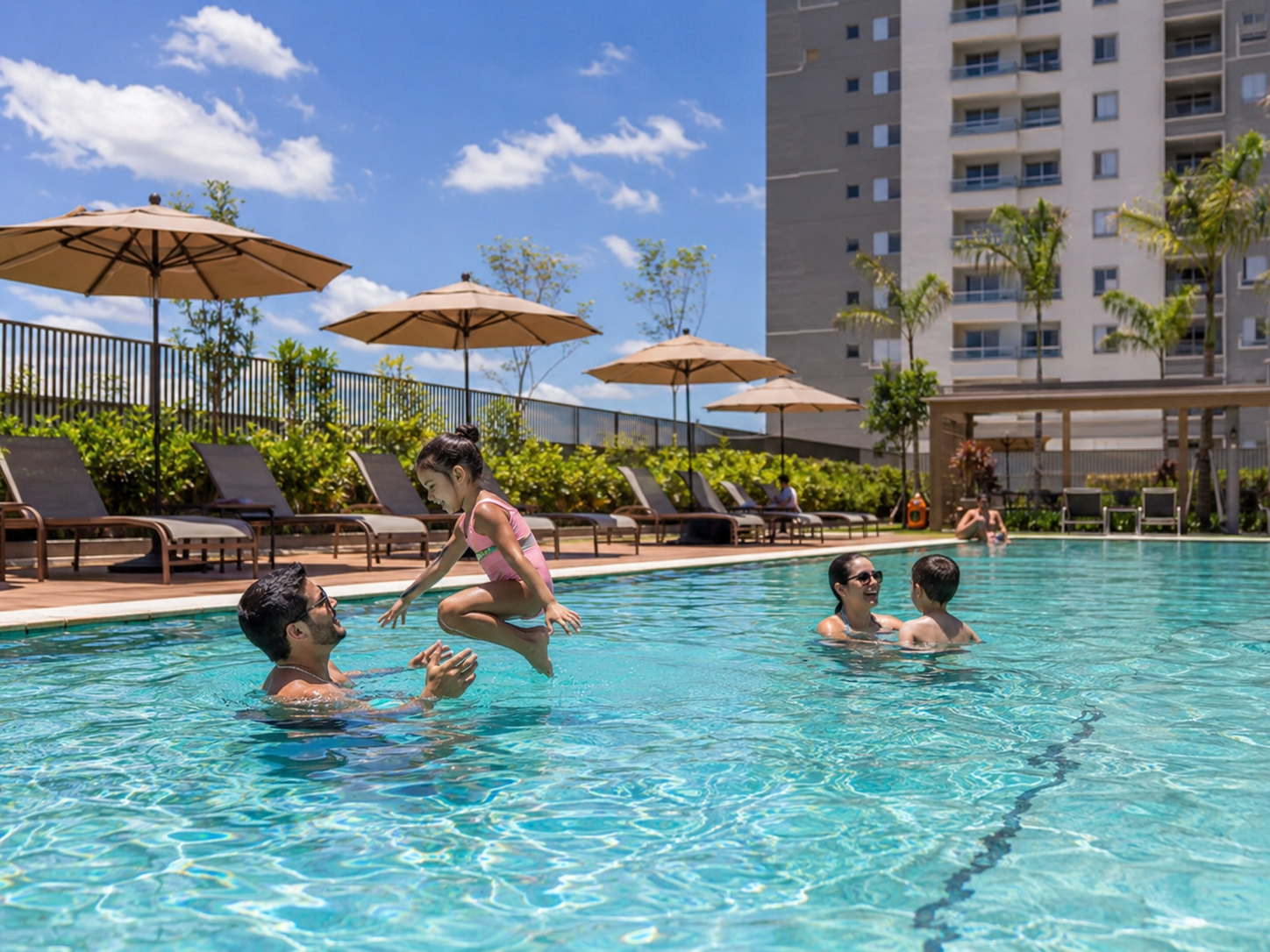 Piscina de condomínio com moradores utilizando a área de lazer